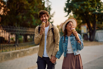 Happy couple enjoying in ice cream while walking in city.