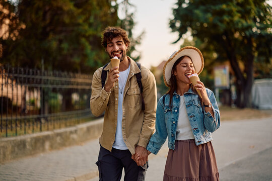 Happy couple enjoying in ice cream while walking in city.