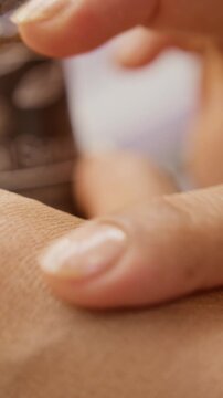 Vertical video of unrecognizable woman applying cosmetic serum from pipette onto hand skin and massaging it. Clip suitable for skincare product advertising, ecommerce campaigns, and beauty tutorials