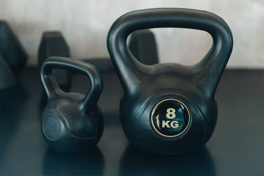 Black kettlebell pair on dark surface, featuring different weights and sturdy handles for strength training
