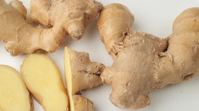 Fresh ginger root and slices on white background