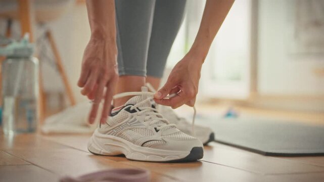 Standing in her kitchen, girl tightens the laces of white sneakers, readying herself for home workout, this simple ritual marks the first step toward a regular exercise habit and an active lifestyle