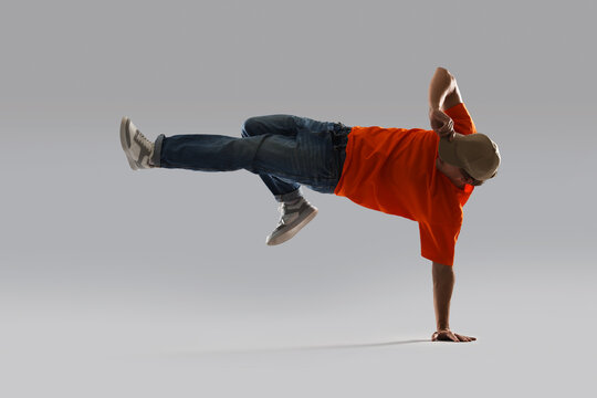 Young man dancing hip-hop on light grey background