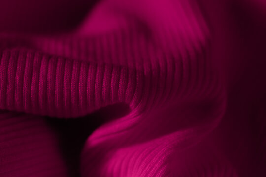 Dark magenta burgundy ribbed knit fabric texture macro close up with elegant soft folds
