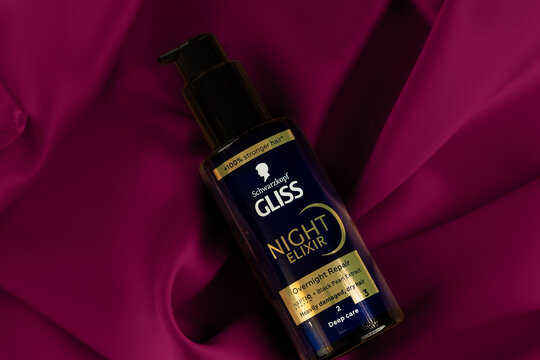 Schwarzkopf Gliss Night Elixir hair serum bottle on burgundy silk background
