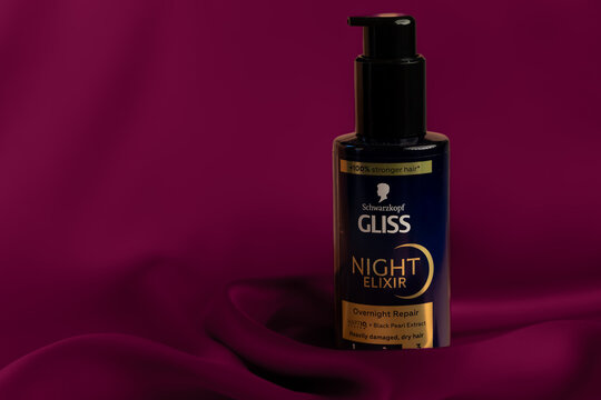 Schwarzkopf Gliss Night Elixir hair serum bottle on burgundy silk background