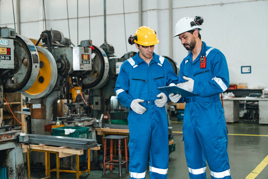 Factory worker industrial technician manufacturing worker safety helmet blue coverall machine factory inspection clipboard teamwork