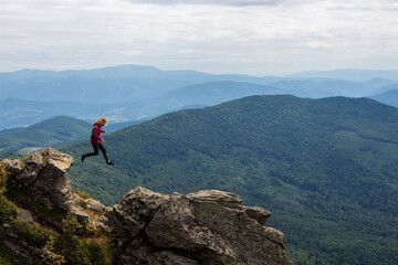 Adventurous young man jumping between rocks on top of a mountain. © Nataliia Zaitova
