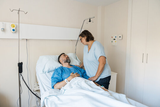 Wife supporting husband patient in hospital bed
