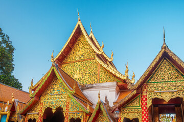 Fototapeta premium Ornate traditional Lanna temple buildings with golden carvings and colorful decorative gables at Wat Phra That Doi Suthep in Chiang Mai, Thailand. Buddhist architecture, Thai culture