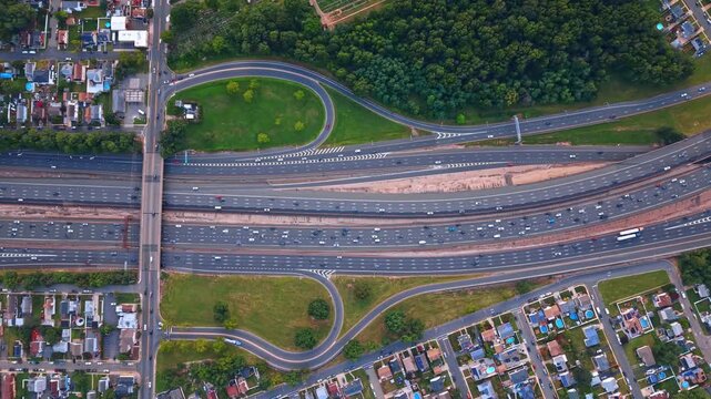 Footage high over the massive freeway system of multi-lane expressways. Heavy traffic of diverse vehicles navigating by the motorways.
