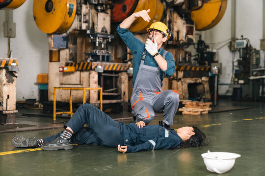 Industrial worker workplace accident factory floor injured worker safety helmet protective clothing fallen colleague emergency response metal press