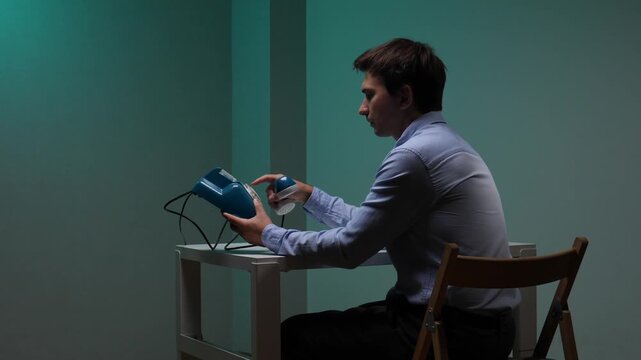 Young man sitting at a desk and dialing a number on a blue retro push button telephone, connecting with the past, highlighting vintage communication in a modern setting