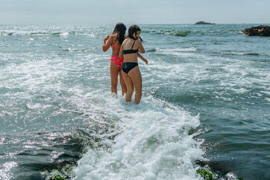 Two Girls Wading Into Ocean Waves on a Sunny Summer Day