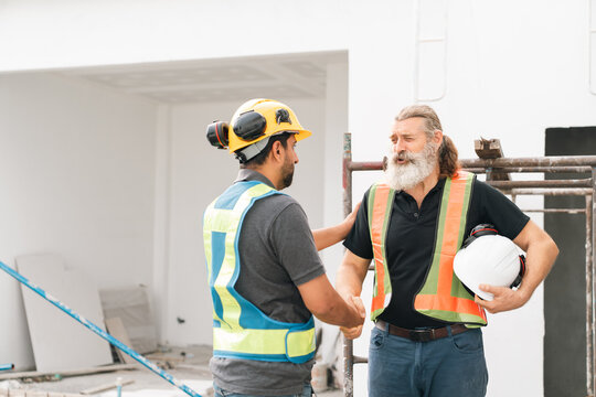 Construction worker contractor safety vest hard hat handshake construction site teamwork between construction workers supports safe building project