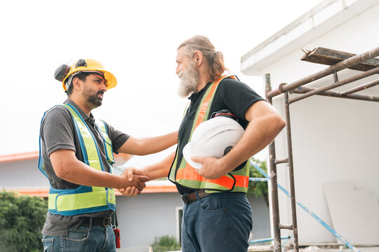 Construction worker safety vest hard hat handshake building site teamwork collaboration during site inspection