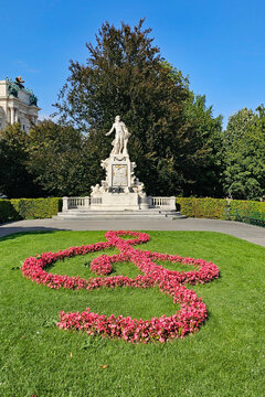 A wonderful photo of a Mozart statue with flowers arranged to form a musical clef, taken in Vienna on a beautiful day