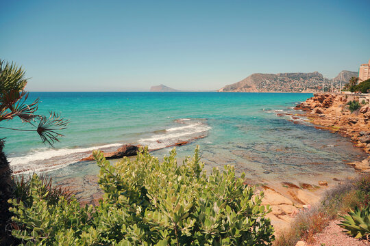 Scenic rocky coastline with green Mediterranean plants and clear turquoise sea water in Calpe, Costa Blanca, Spain