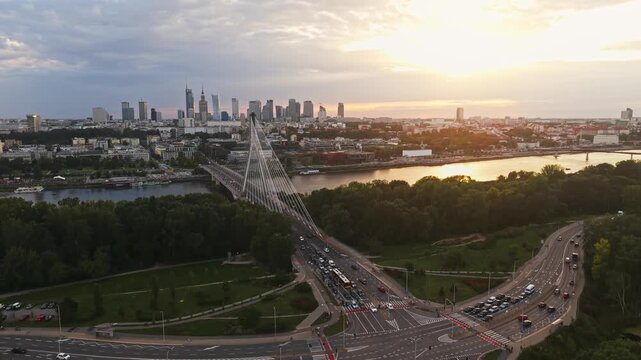 Wide angle rising drone establishing aerial shot of Warsaw skyline at golden hour, with modern skyscrapers, city center, Vistula River and cable-stayed bridge in cinematic view