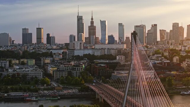Rising drone establishing aerial shot of Warsaw skyline at golden hour, with modern skyscrapers, city center, Vistula River and cable-stayed bridge in cinematic view
