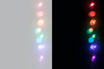 Plakat Vertical string of colorful glowing Christmas lights. Multi-colored illuminated bulbs on transparent PNG and black backgrounds. Festive holiday decoration design element.