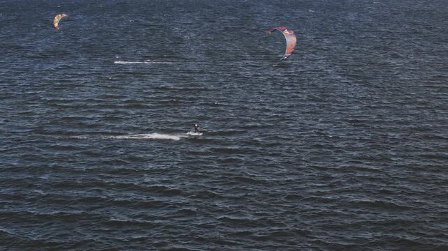 Tallinn, Estonia-September 28, 2025: Aerial perspective captures a kitesurfer maneuvering across the water, with a vibrant kite soaring above, showcasing the dynamic movement and fluidity of the sport