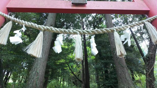 Shimenawa rope and shide paper on a red torii gate at a Japanese Shinto shrine