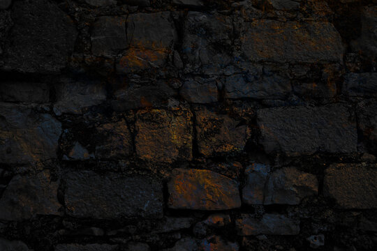  Textura de pared de ladrillo y roca oscura erosionada. Superficie de pared geol&oacute;gica rugosa con tonos oscuros; transmite solidez, resistencia industrial y antig&uuml;edad.
