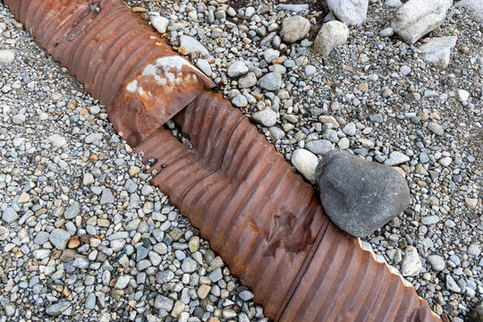 Rusted Corrugated Pipe on Rocky Gravel Beach With Stone and Pebble Texture in BC Canada