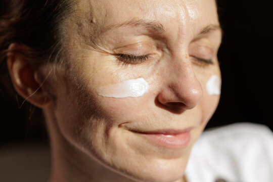 Mature Woman With Face Cream in Warm Morning Sunlight