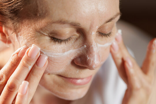 Mature Woman Applying Face Cream in Warm Morning Sunlight