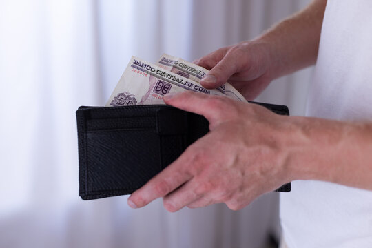 Man holding 100 Cuban peso banknote and wallet