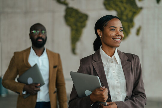 African american business team walking with laptops in office
