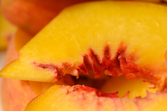 Commercial stock photo of a macro view focusing on the textured red-flecked core of a fresh peach slice