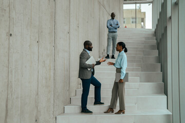 Business professionals collaborating on modern office staircase discussing work
