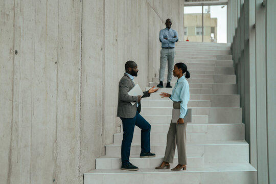 Business professionals collaborating on modern office staircase discussing work