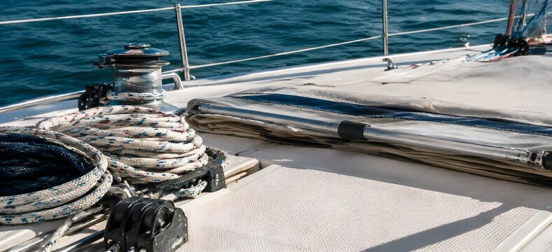 Sailing gear and coiled ropes arranged neatly on empty sailboat deck