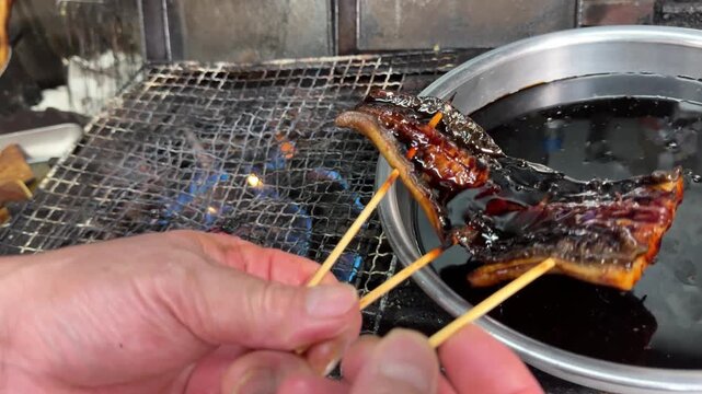 Grilled Eel with Sweet Soy Sauce: Dipping Skewered Unagi Kabayaki in Sauce and Grilling over Fire, Traditional Japanese Food