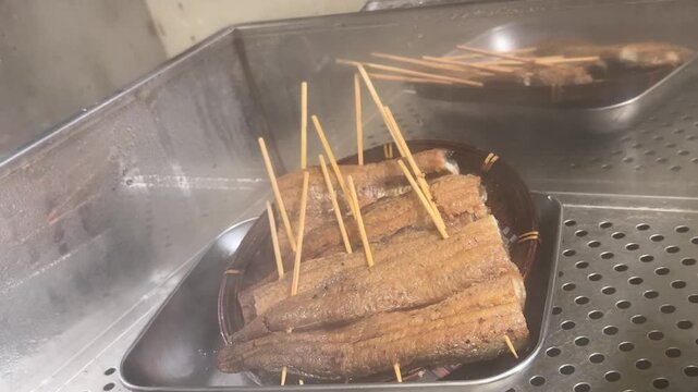 Grilled Eel (Unagi Kabayaki) in a Steamer: Hand Opening the Lid on Skewered Eel, Traditional Japanese Summer Stamina Food