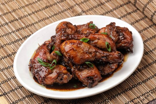 Chicken adobo, a classic Filipino dish made with tender chicken simmered in a savory soy sauce and vinegar marinade with garlic and spices, served with steamed white rice.