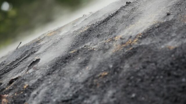 Close up of smoke rising from smoldering charcoal kiln mound in traditional charcoal production