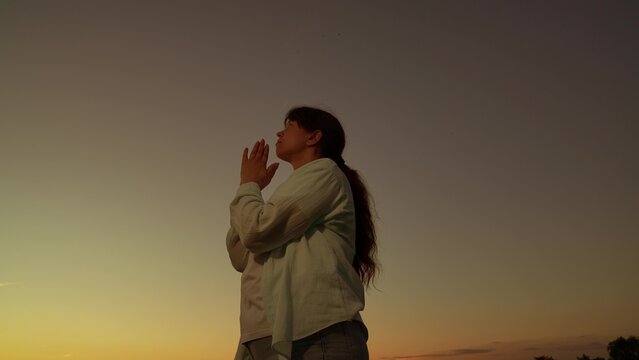 Woman asking God for help. Relaxation, meditation, nature. Woman prayer. Christian girl praying sunset, close-up. Faith God. Woman praying for her family, children, morning sky. Hope. Religious people