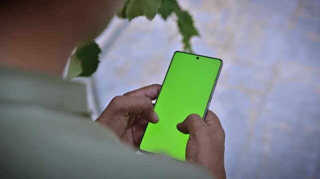 Hands holding smartphone green screen mockup with nature background, chroma key mobile display for app mockup and video screen replacement