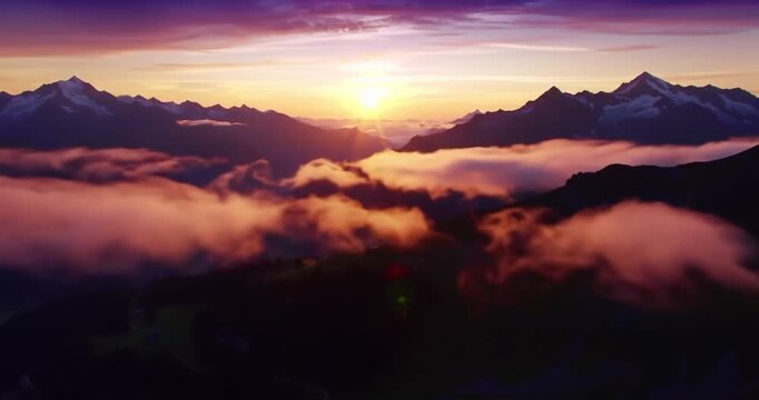 Aerial sunrise view over majestic mountain peaks and rolling clouds