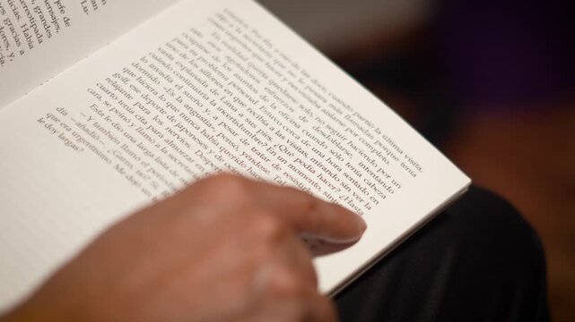 Close-up of a finger carefully tracing printed lines of text on a Spanish book page.