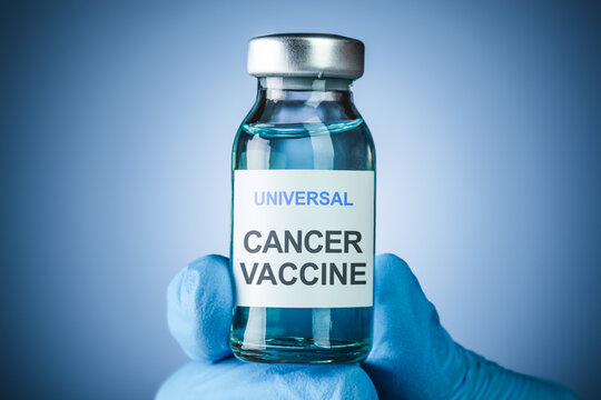 Nurses hand in blue medical gloves holding a vaccine bottle with Universal Cancer Vaccine text. Health care concept of comprehensive vaccines for prevention or treatment of various cancers.