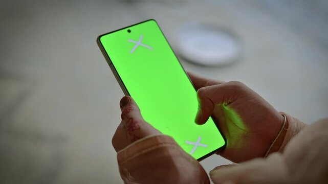 Female hands holding modern smartphone green screen mockup, close up of woman using mobile phone chroma key display for app interface and video editing replacement