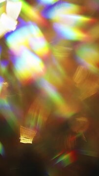 Dreamy bokeh of a golden shimmer and dazzling rainbow lens rays. Real optical effect of shining gold creating an aura of luxury and a visual of glamorous glittering lights and sparkling reflections.