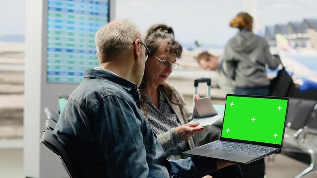 Chroma key on a laptop screen used by senior people in an airport lounge to check an itinerary and plan the next adventure before their flight.