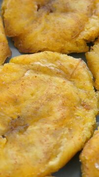 Fried platanos on plate. Sliced and cooked tostones. Rotating. Vertical footage